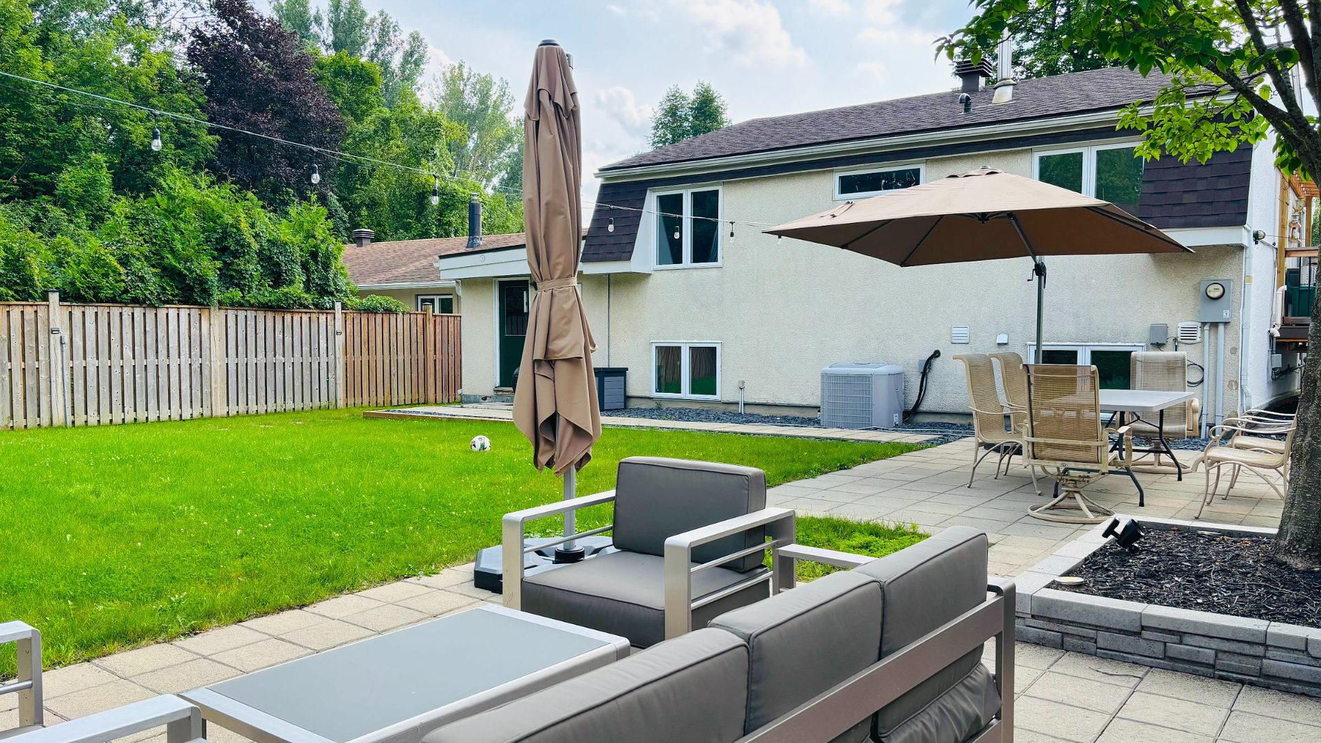 The finished yard: lounge set on new pavers, lawn beyond